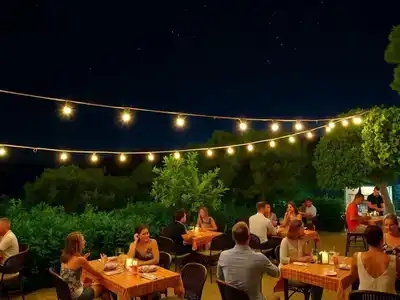 Couples enjoying nightlife on Mljet under string lights.