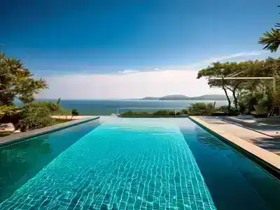 An infity poool surrounded by trees and overlooking a deep blue sea