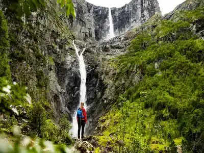 A hiker looking up to the Mardalsfossen waterfall.