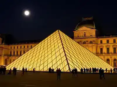 Louvre Museum illuminated at night with visitors exploring.