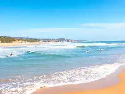 Surfers riding waves on a sunny French beach.