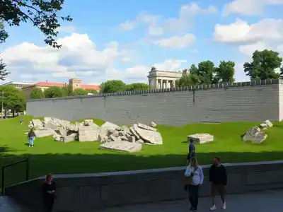 Berlin Wall Memorial with visitors and greenery in background.