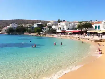 Beach in Crete with sunbathers and clear blue skies.