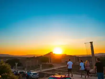 Sunset over ancient ruins in Rhodes with visitors.