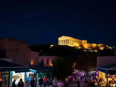 Nighttime view of Athens with illuminated ancient ruins.