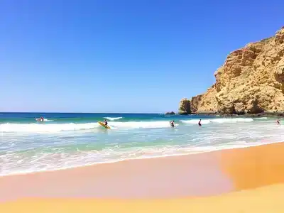 Surfers riding waves at Playa de la Albufereta beach.