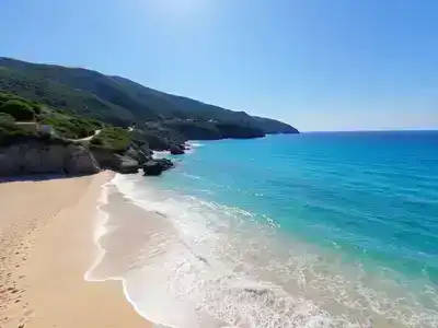 Sandy beach in Turkey with turquoise waters and greenery.