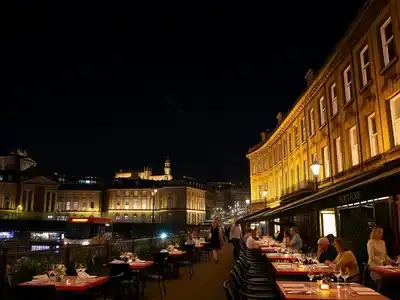 Edinburgh skyline at night with bustling outdoor gourmet dining tables.